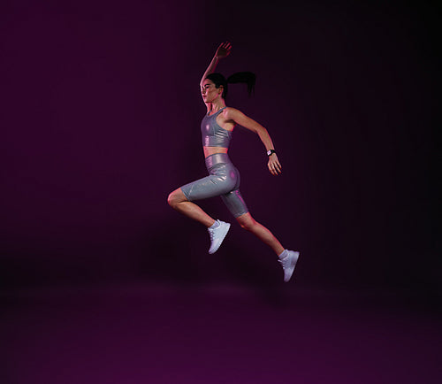 Full length of slim woman jumping against magenta backdrop