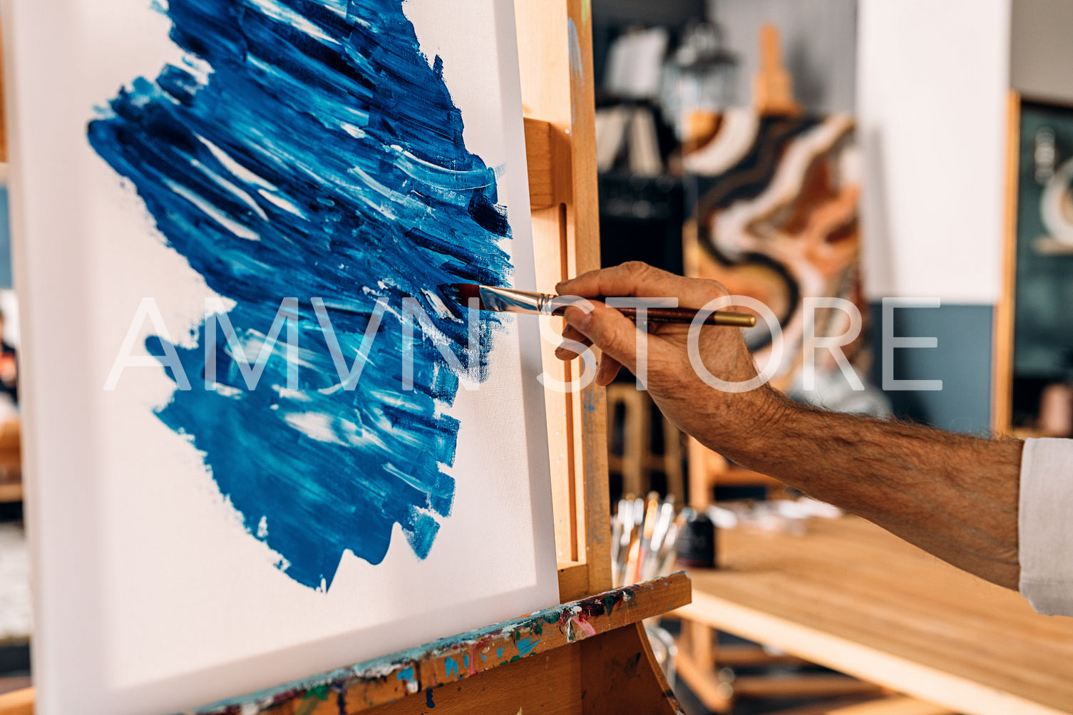 Hand of a painter holding a brush and drawing on canvas	