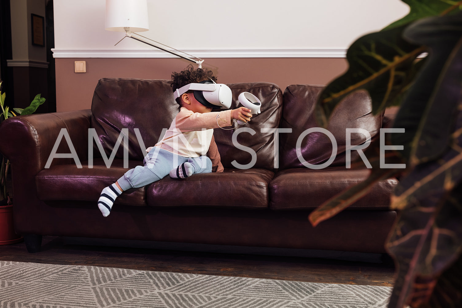 Little boy wearing VR glasses while sitting on sofa. Kid with virtual reality goggles and controller playing a video game at home.