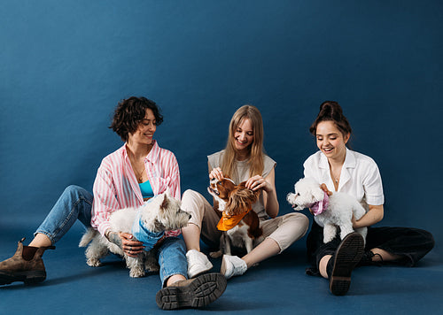 Three happy women sitting on a blue background with their cute d