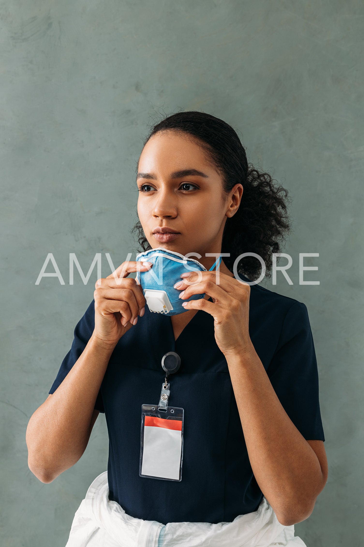 Portrait of female medical worker wearing a respirator at wall and looking away	