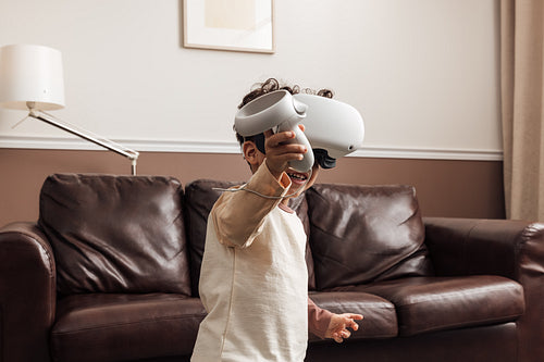 Little smiling boy wearing VR goggles using a controller for int