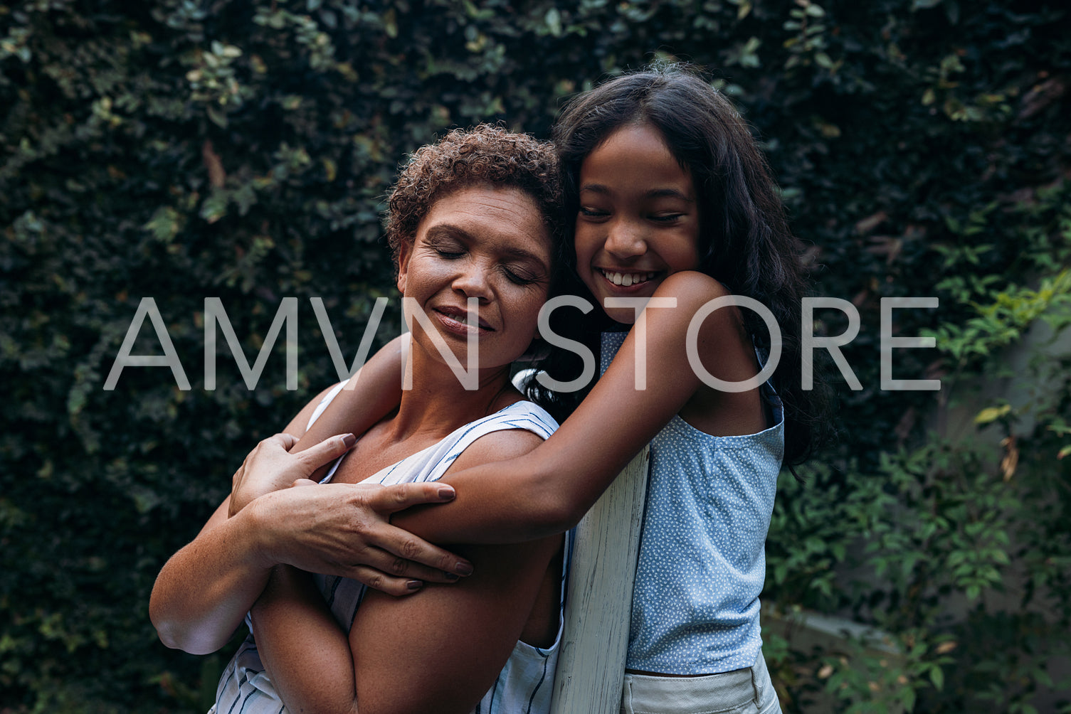 Smiling girl and her grandma outdoors. Kid and grandmother holding each other at backyard.