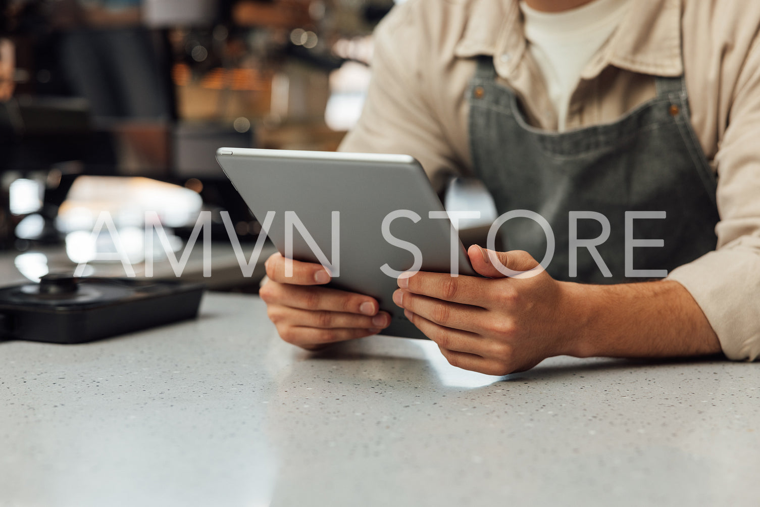 Close-up of hands holding a digital tablet. Unrecognizable bartender in an apron holding a portable computer at the counter.