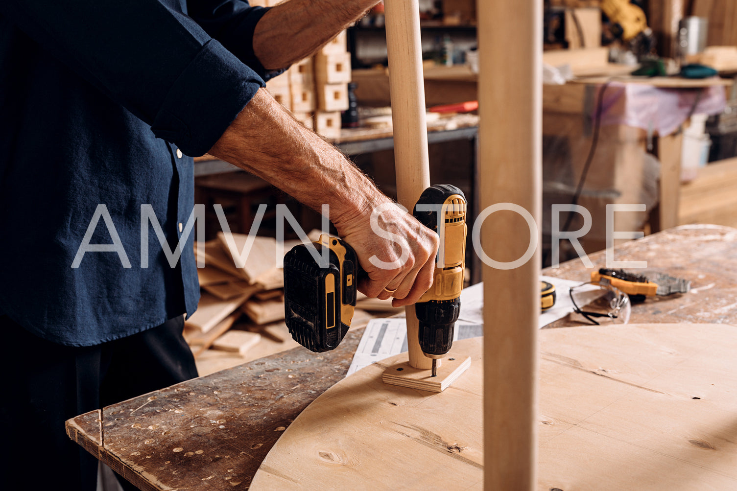 Unrecognizable senior male carpenter drilling a hole in wooden table	