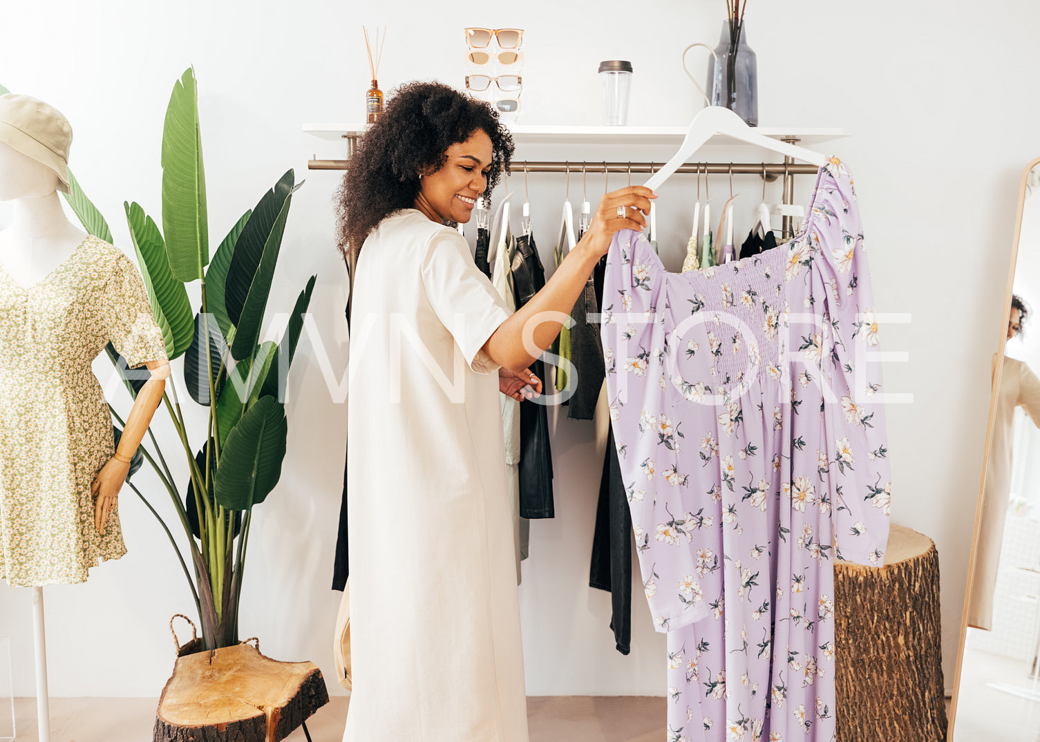 Woman choosing a dress. Side view of young stylish female standing near rack with hanger.