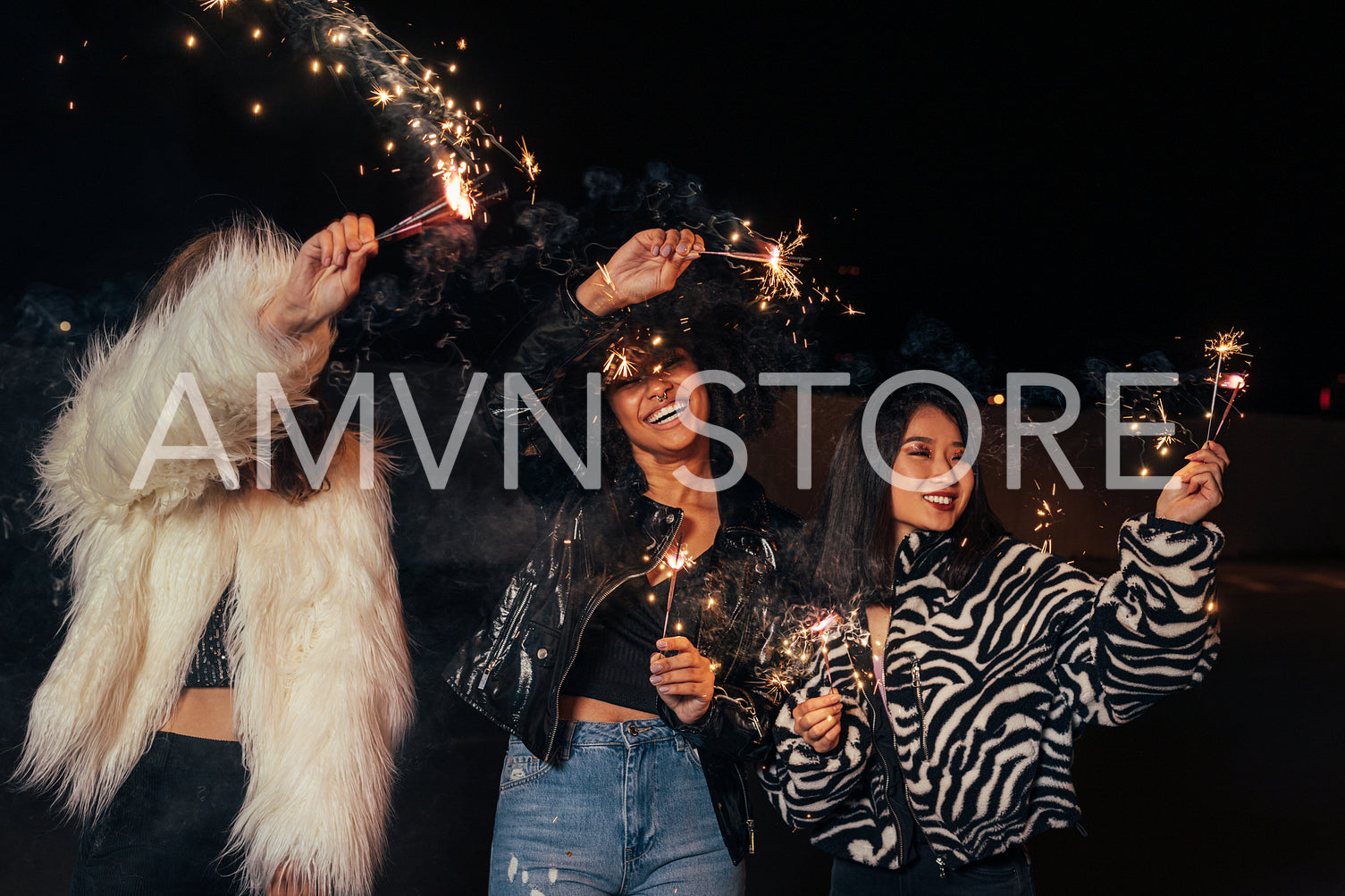 Three happy girls waving sparklers while walking together at night	