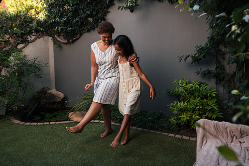 Grandma and a kid having fun together in backyard. Grandmother teaching granddaughter to dance moves.