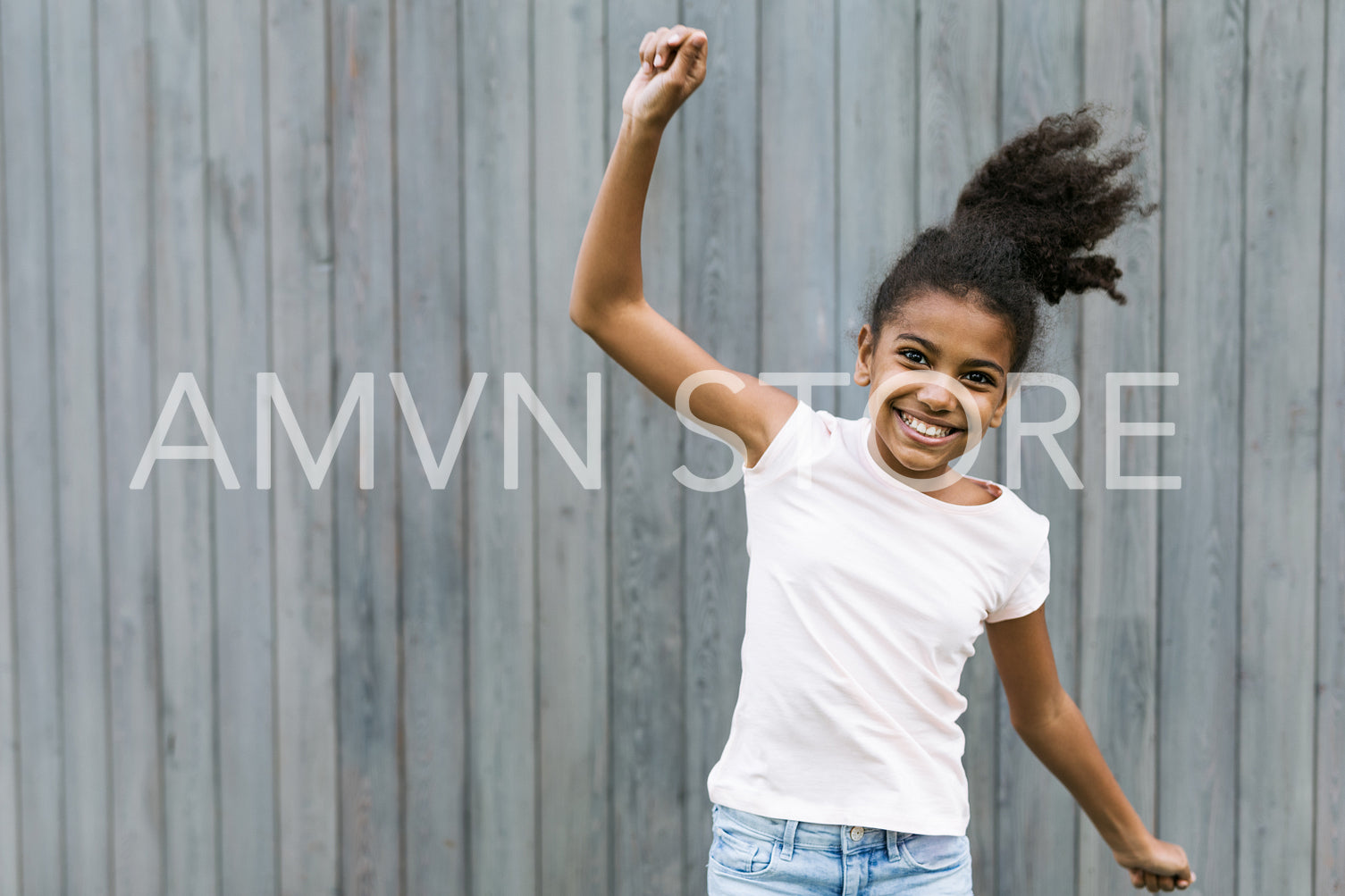 Happy girl jumping near a wall outdoors	