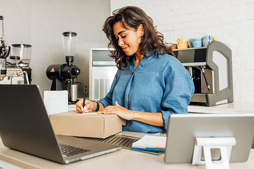 Smiling entrepreneur woman finishes preparing the parcel for shipment