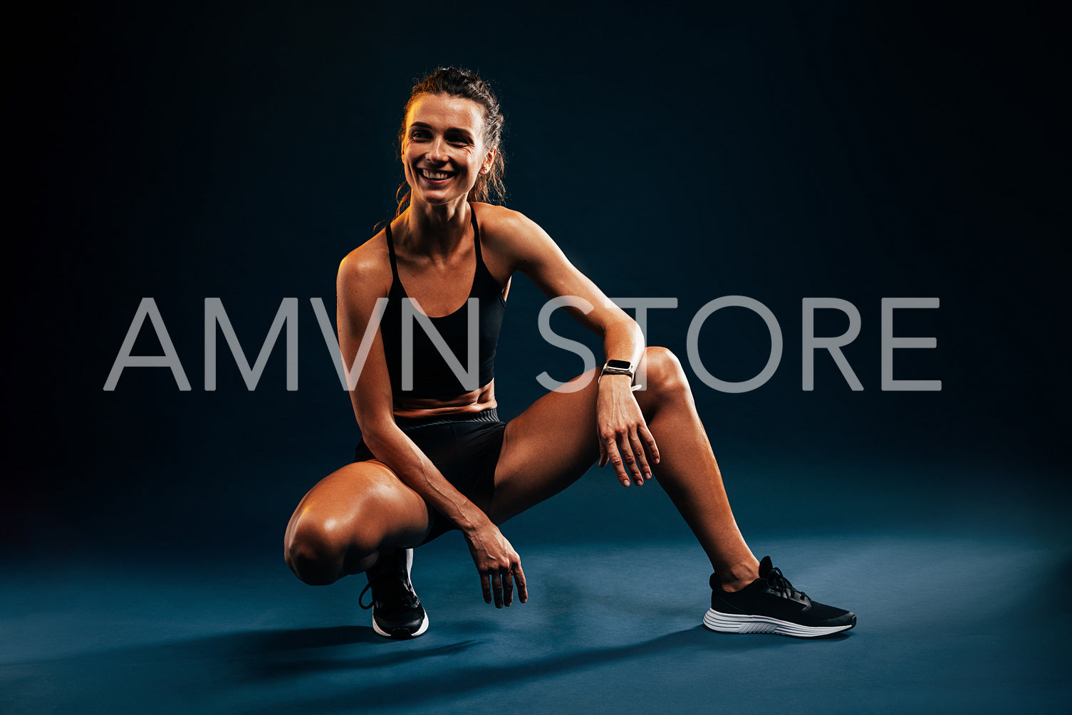 Woman in sport clothes sitting on black background after training. Smiling runner relaxing after intense workout.