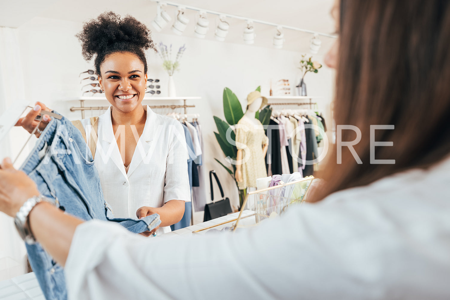 Customer purchase clothes. Unrecognizable employee taking jeans from a buyer at counter.