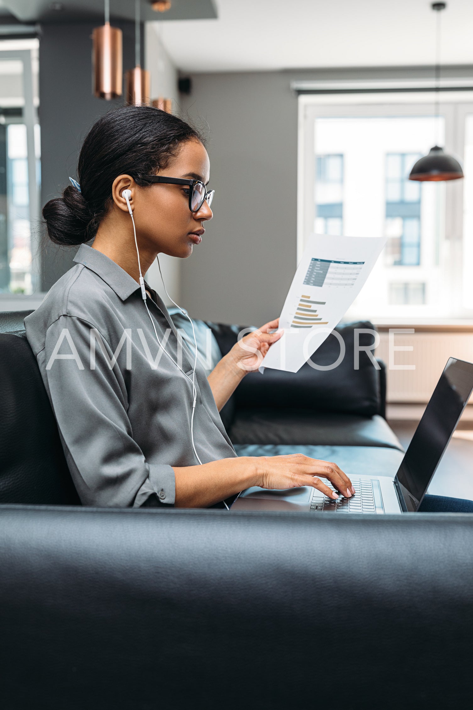 Young businesswoman working from home. Side view of freelancer using laptop computer sitting on the sofa wearing eyeglasses.	