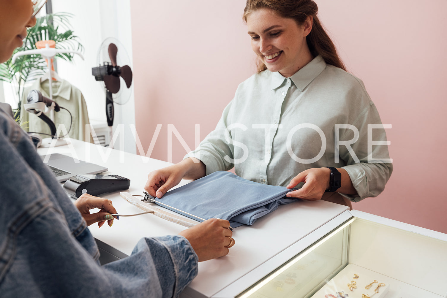 Unrecognizable customer buying clothes from a saleswoman at a fa