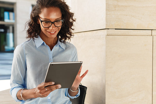 Young woman wearing eyeglasses reading and browsing on digital tablet