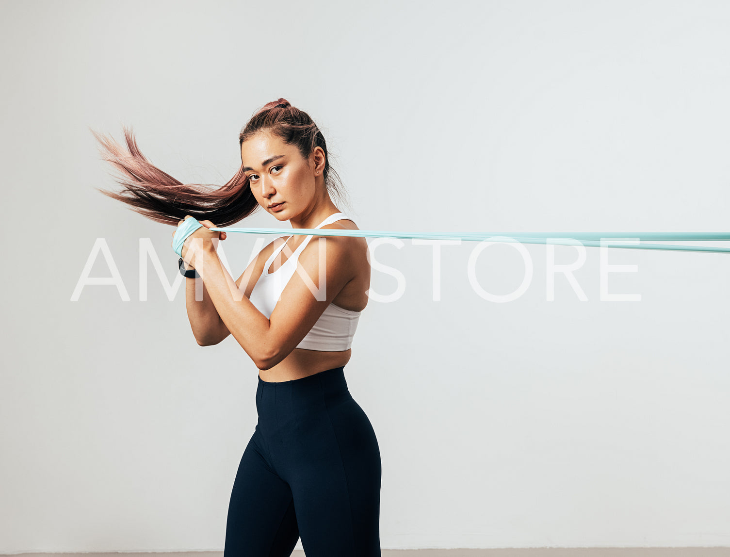 Fitness woman exercising with resistance band looking at camera