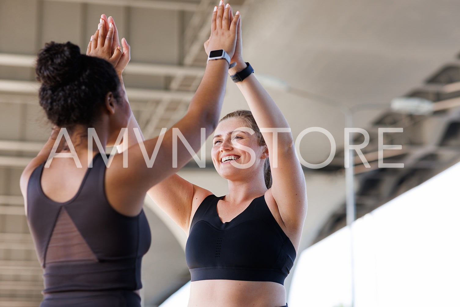 Two cheerful plus-size women in fitness wear giving high five after a workout. Women athletes during fitness training outdoors giving high five.