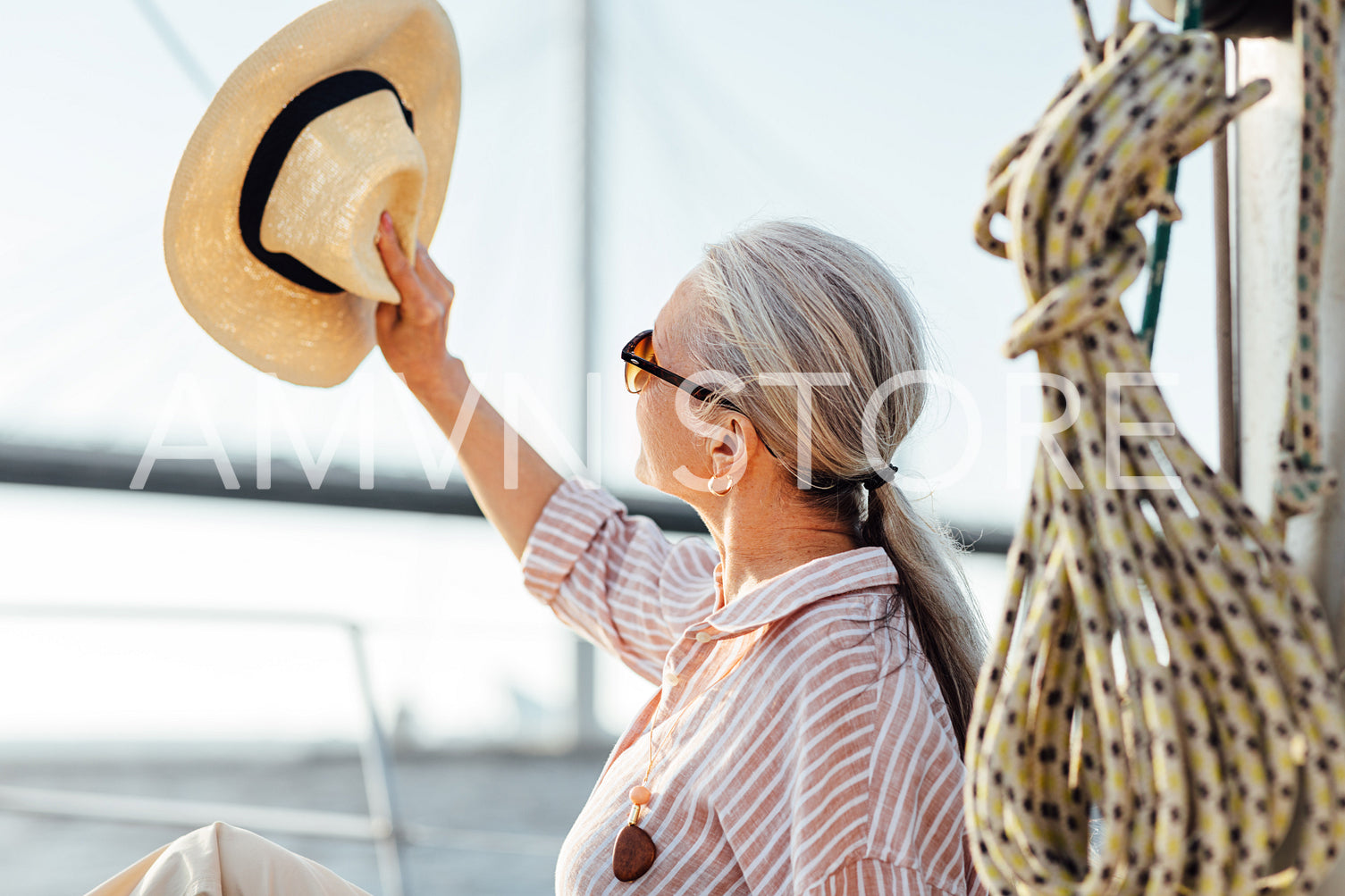 Woman on yacht uses a hat to hide her face from the sun	