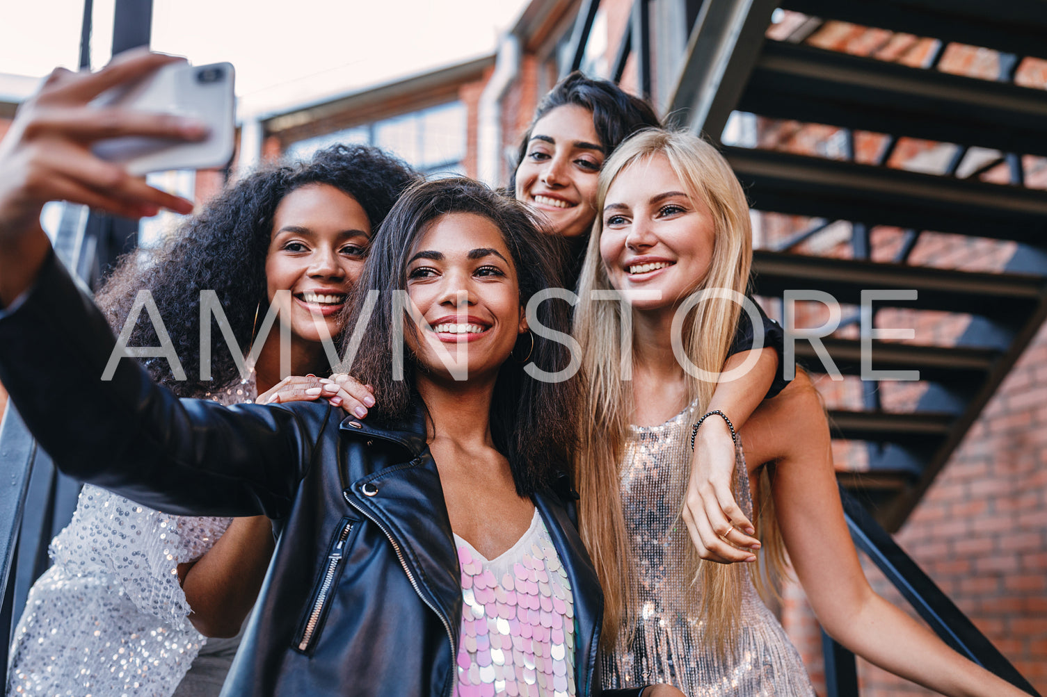 Group of stylish women taking selfie in the city. Four women making photographs on a cell phone.	