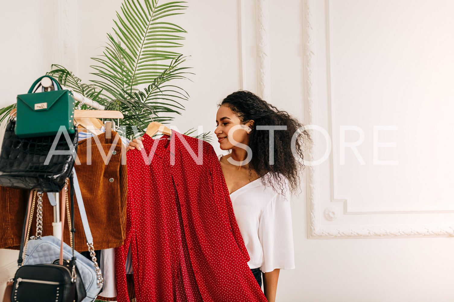 Personal buyer holding a red dress. Young woman at her wardrobe.