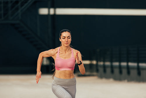 Young muscular runner on the roof. Female jogger exercising on rooftop.