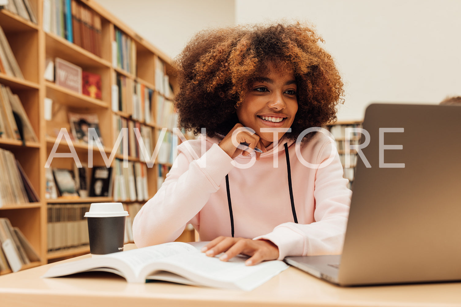 Smiling girl with curly hair looking at laptop and preparing exams