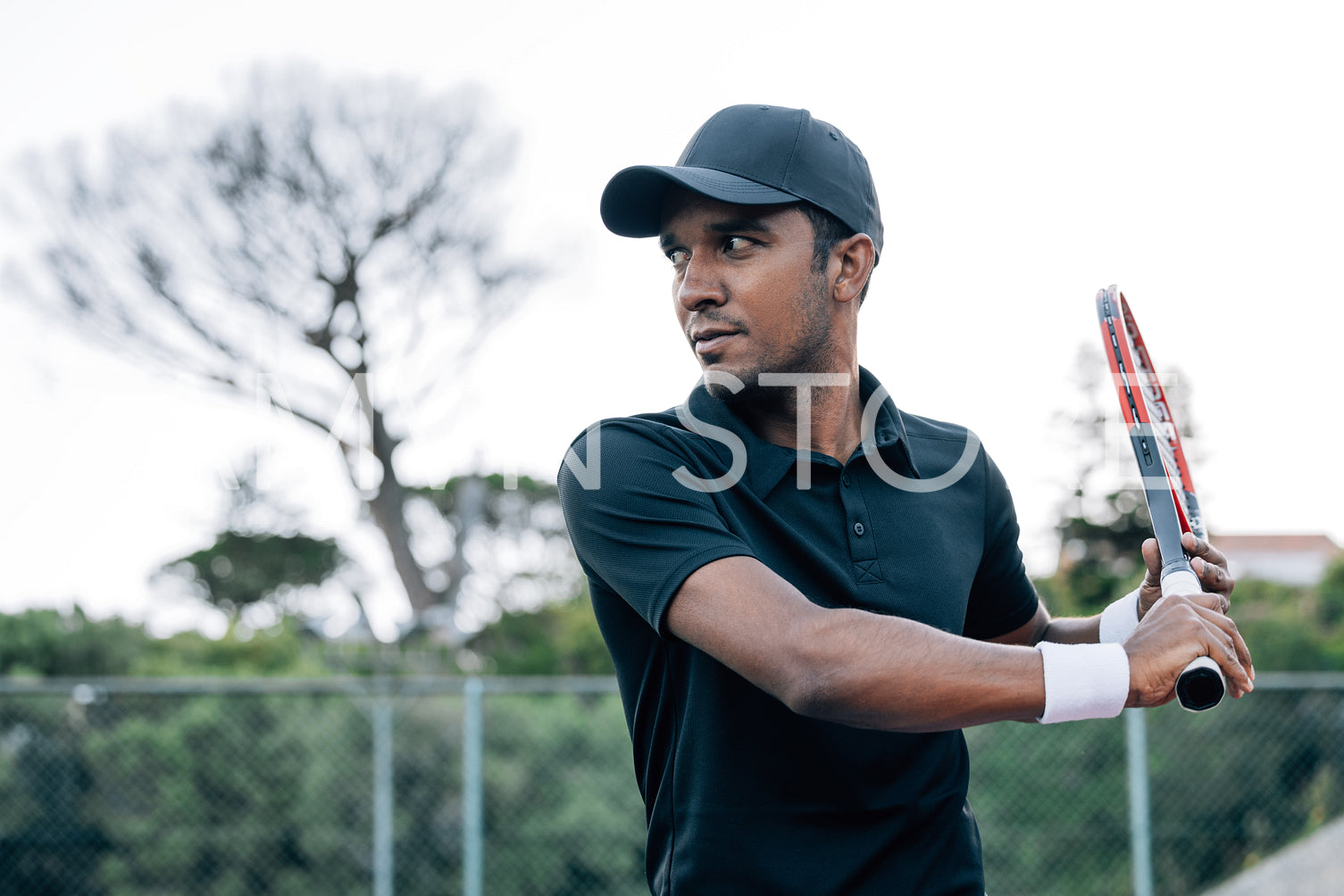 Portrait of a confident tennis player in a cap holding racket