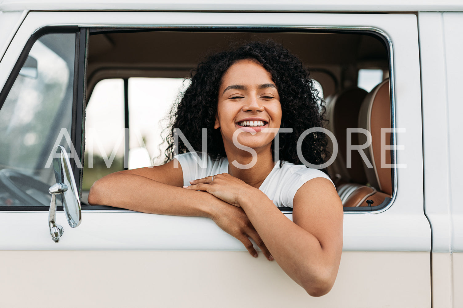 Cheerful brunette woman sitting on a driver seat in a camper van with closed eyes 