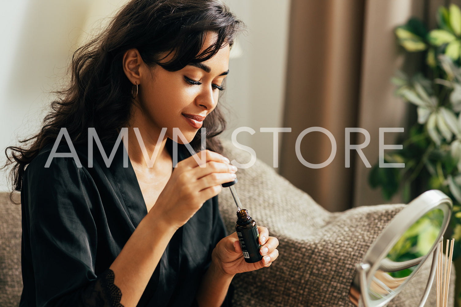 Young woman sitting on a couch holding a bottle with serum preparing for applying