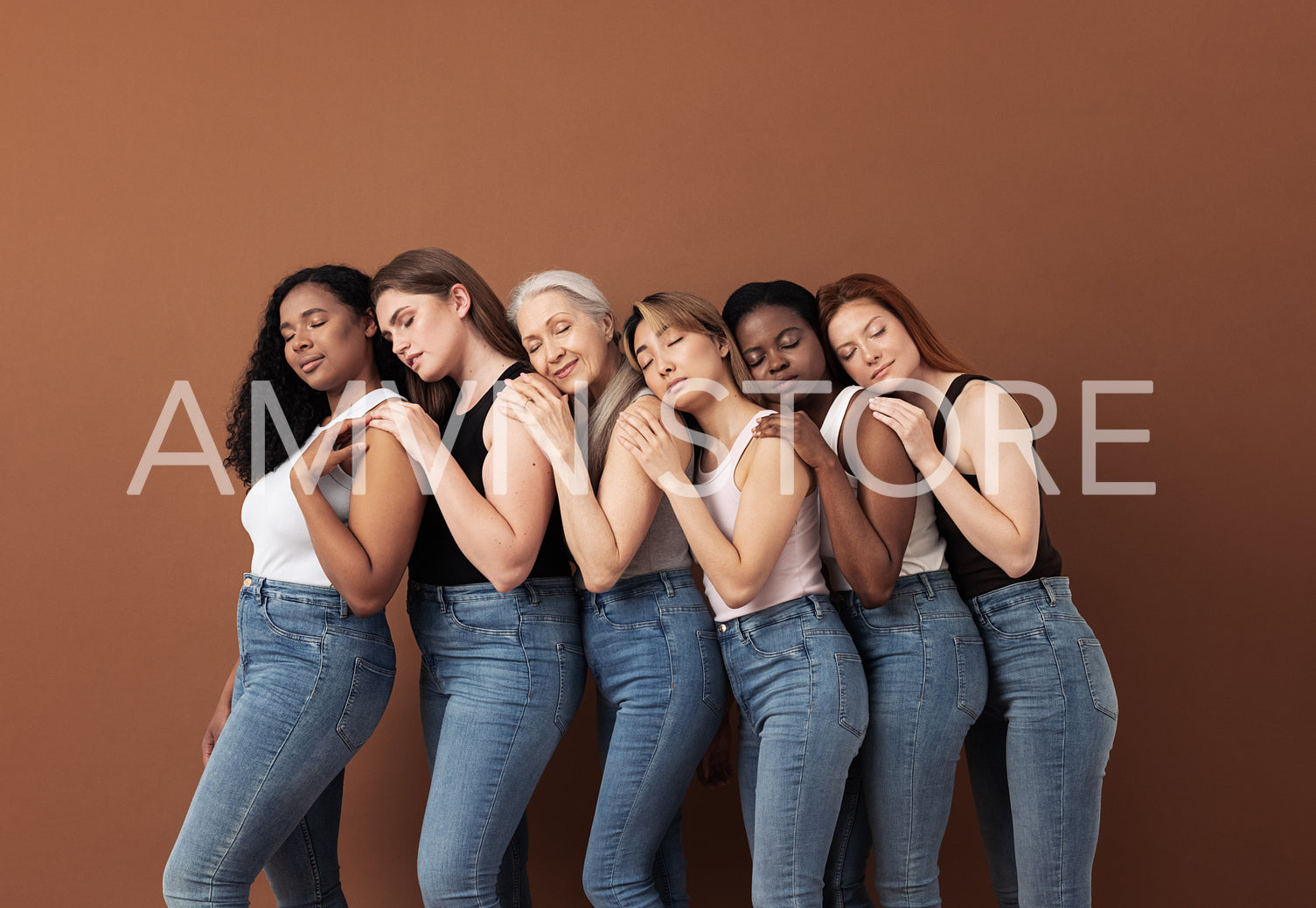 Diverse women in casuals embracing each other while standing with closed eyes over brown background