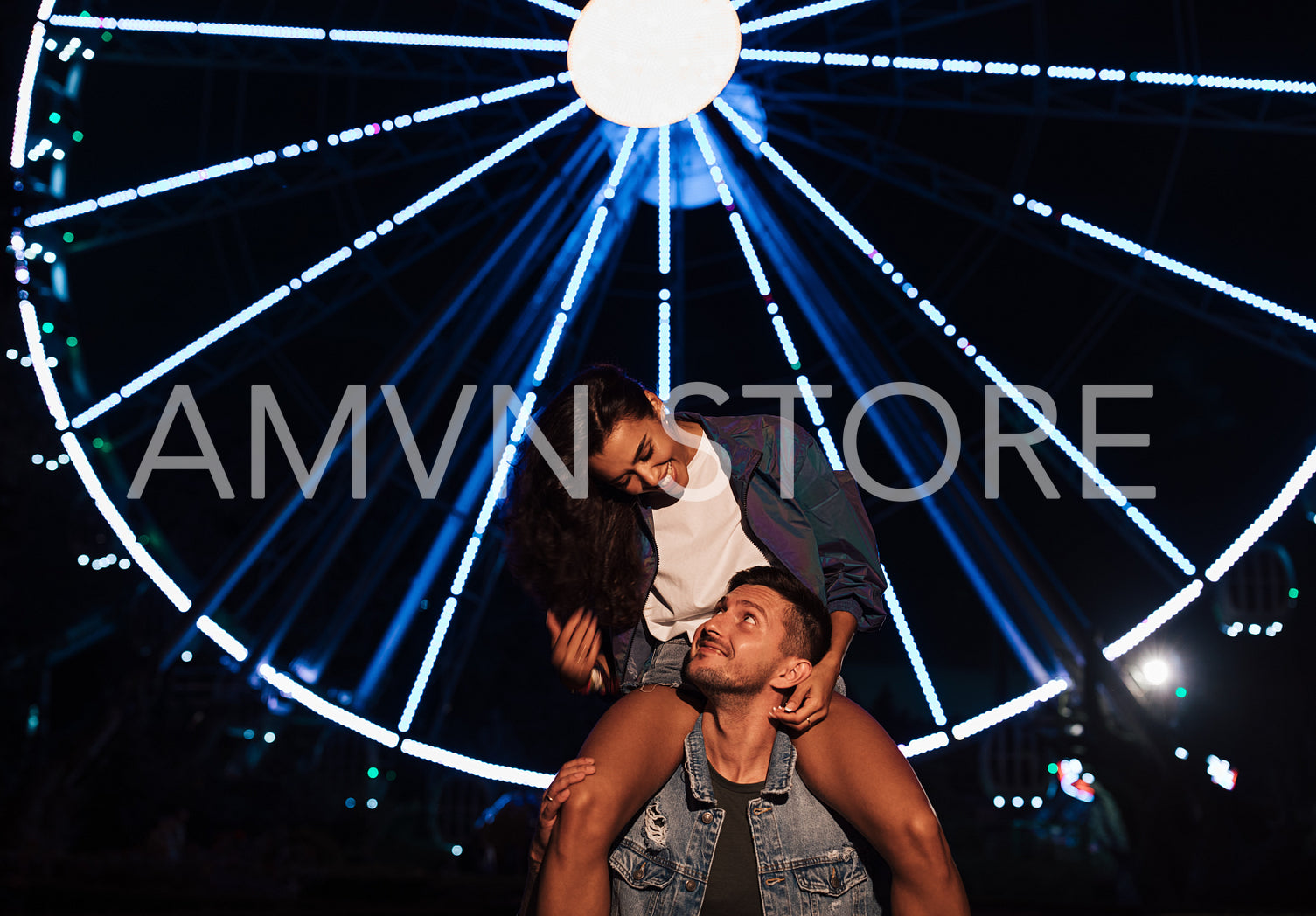 Young female and her boyfriend at night against ferris wheel