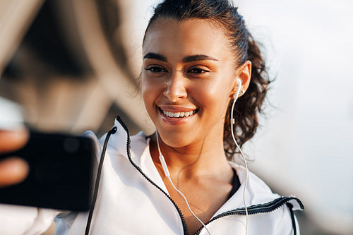 Smiling woman looking on her smartphone during workout taking selfie