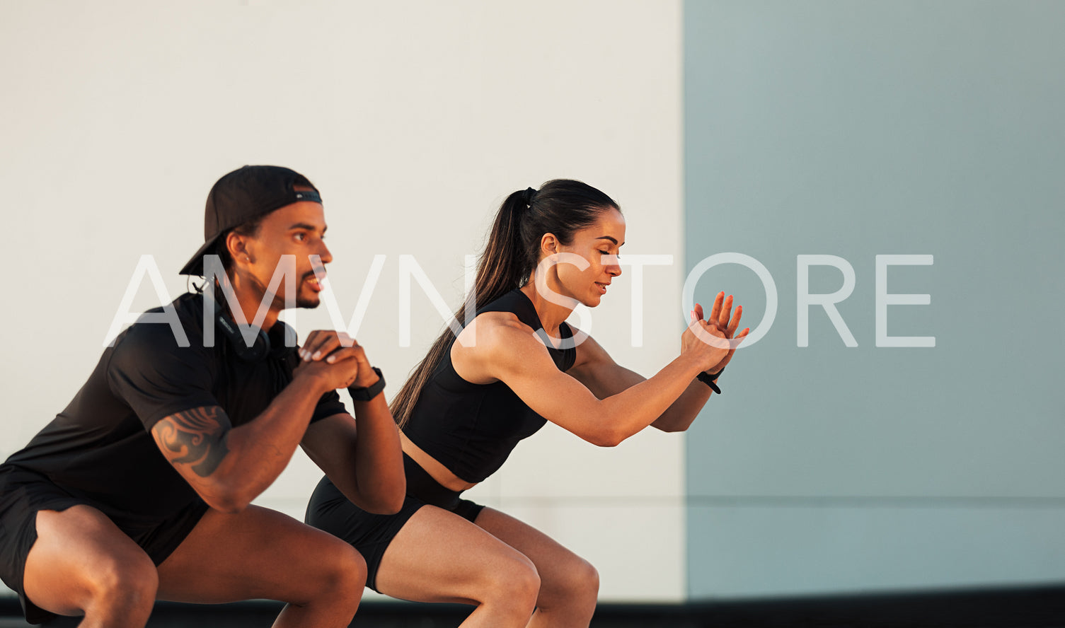 Side view of two athletes ding sit-ups at a wall. Muscular man and woman are training together.