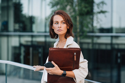 Portrait of a confident businesswoman with ginger hair holding a leather folder