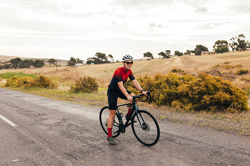 Full length of a pro cyclist taking a break from intense training on country road