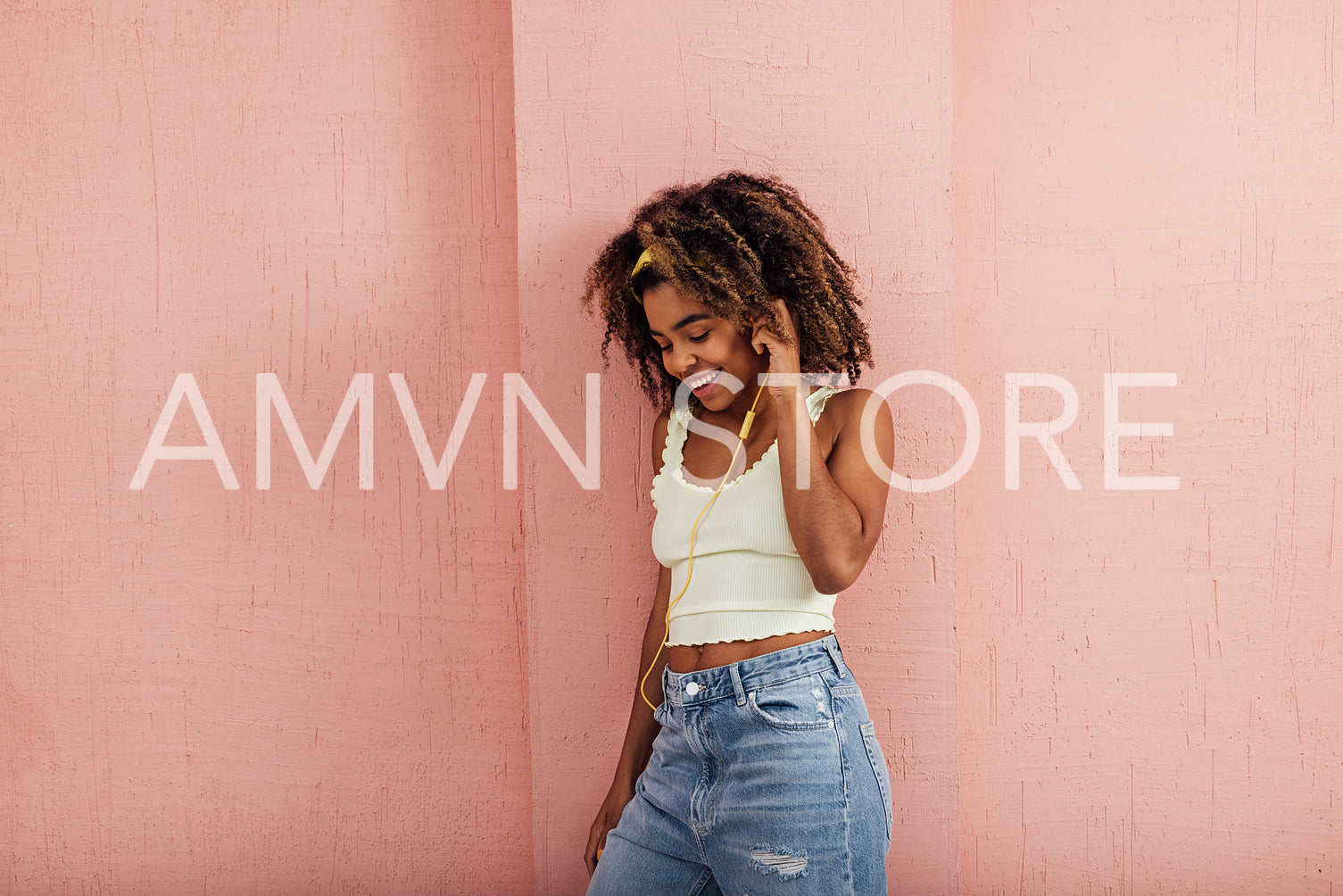 Smiling female enjoying music while standing against wall