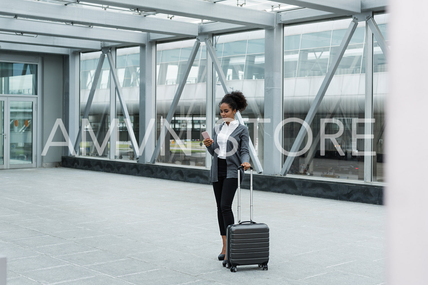 Young woman with luggage and cell phone preparing for business trip	