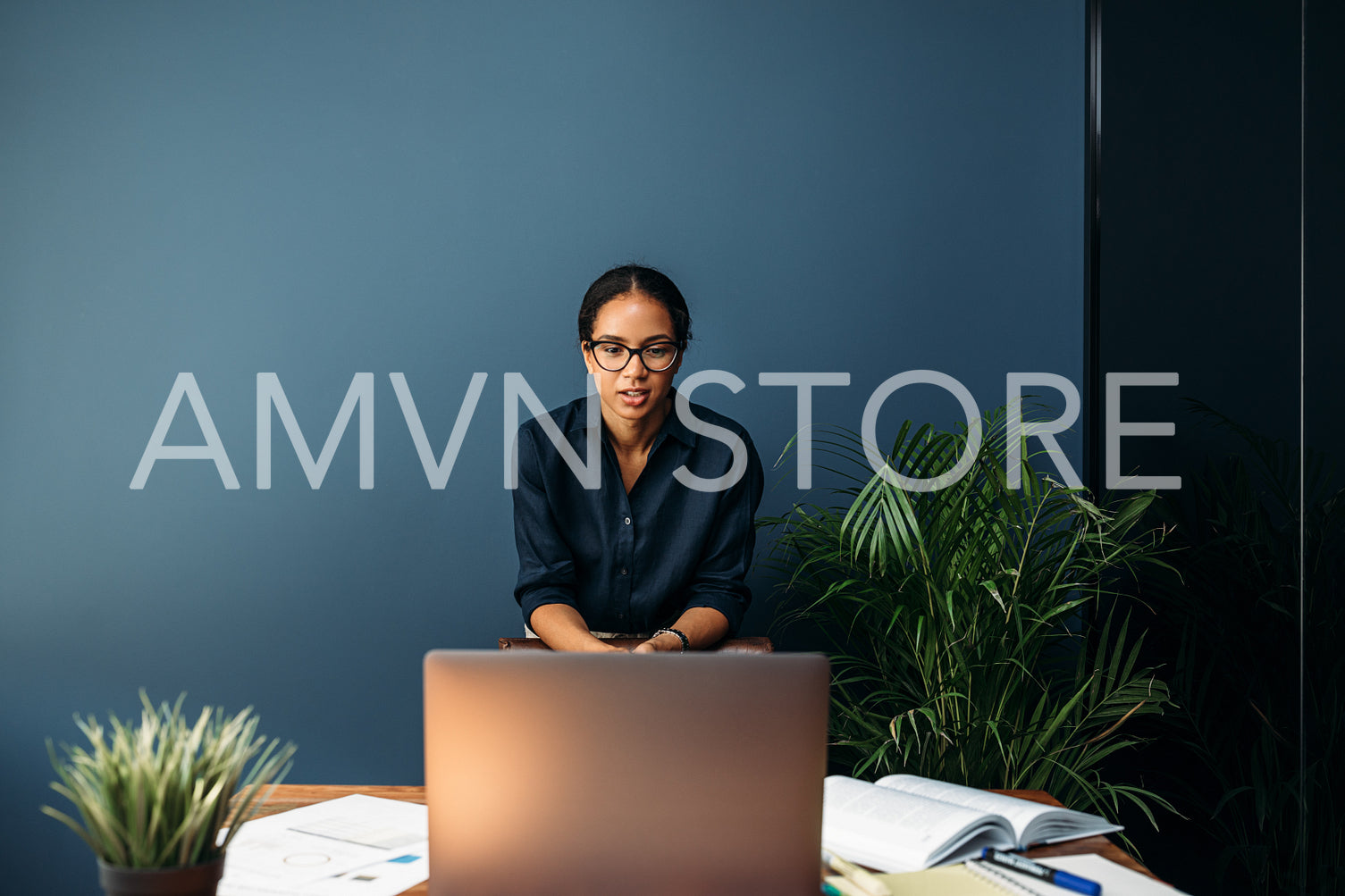 Young businesswoman standing at the desk in home and having a video chat over her laptop	