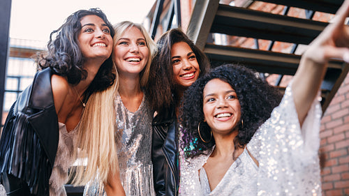 Four women on the street look at one point and smiling