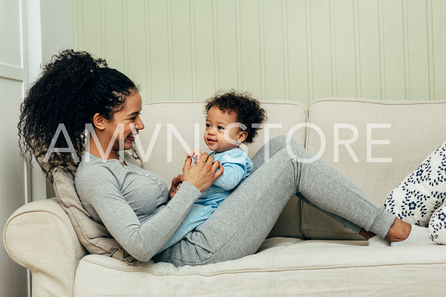 Side view of mother lying on couch and playing with her son	