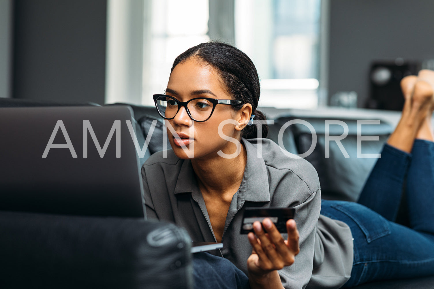 Woman in spectacles holding a credit card and making online payment	