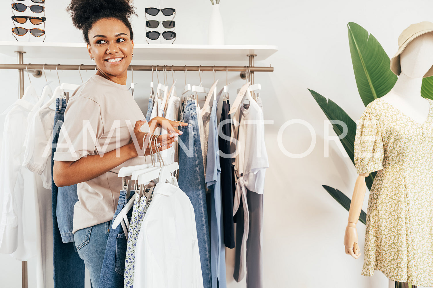 Local boutique owner hanging clothing on rack. Young woman working in a clothing store.