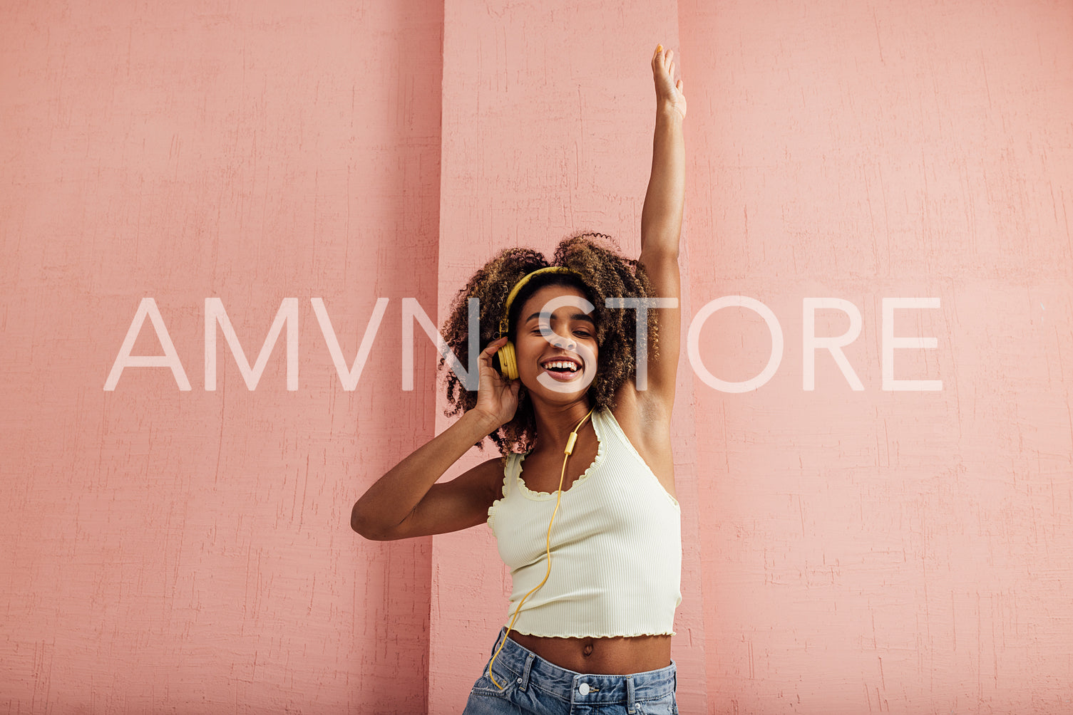 Young woman dancing and raising hand up while listening to music