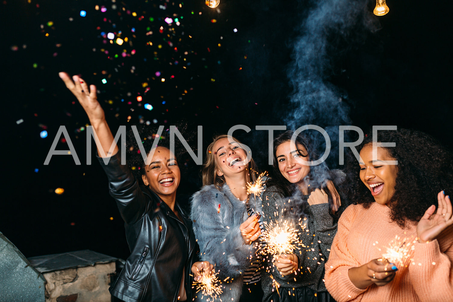 Group of young women celebrating new years eve outdoors, throwing confetti	