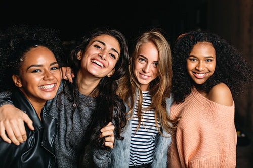 Four beautiful women looking at camera, standing outdoors at night