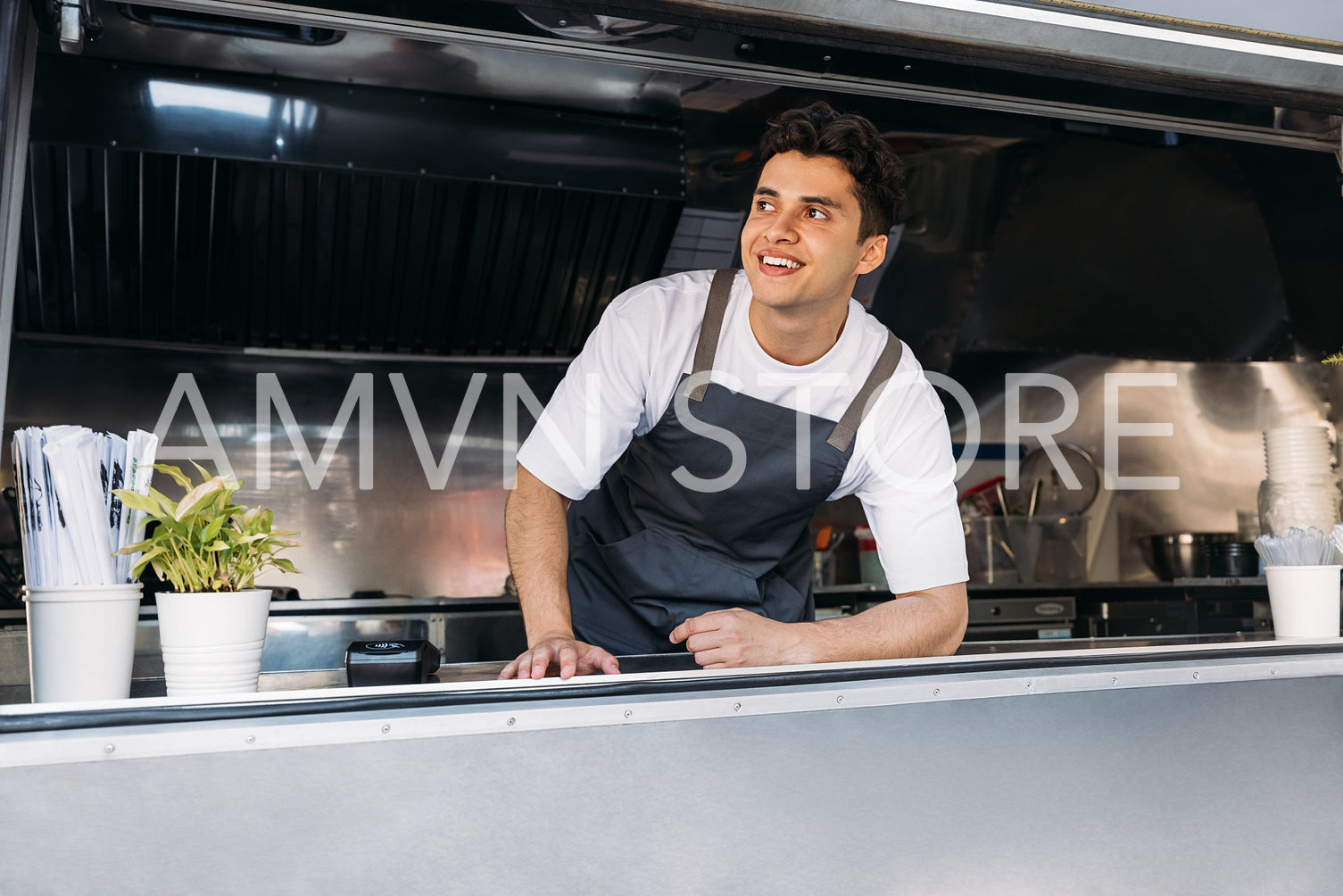 Portrait of a smiling food truck owner wearing apron leaning counter