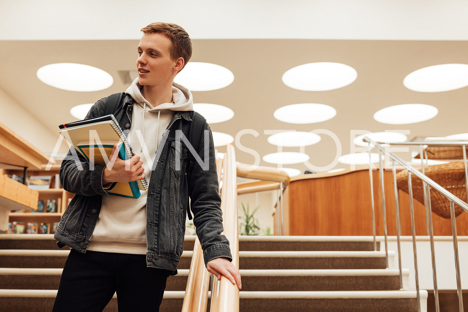 University student holding books going down the stairs in library