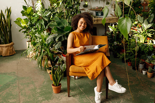 Woman botanist working at her indoor garden sitting on an armchair