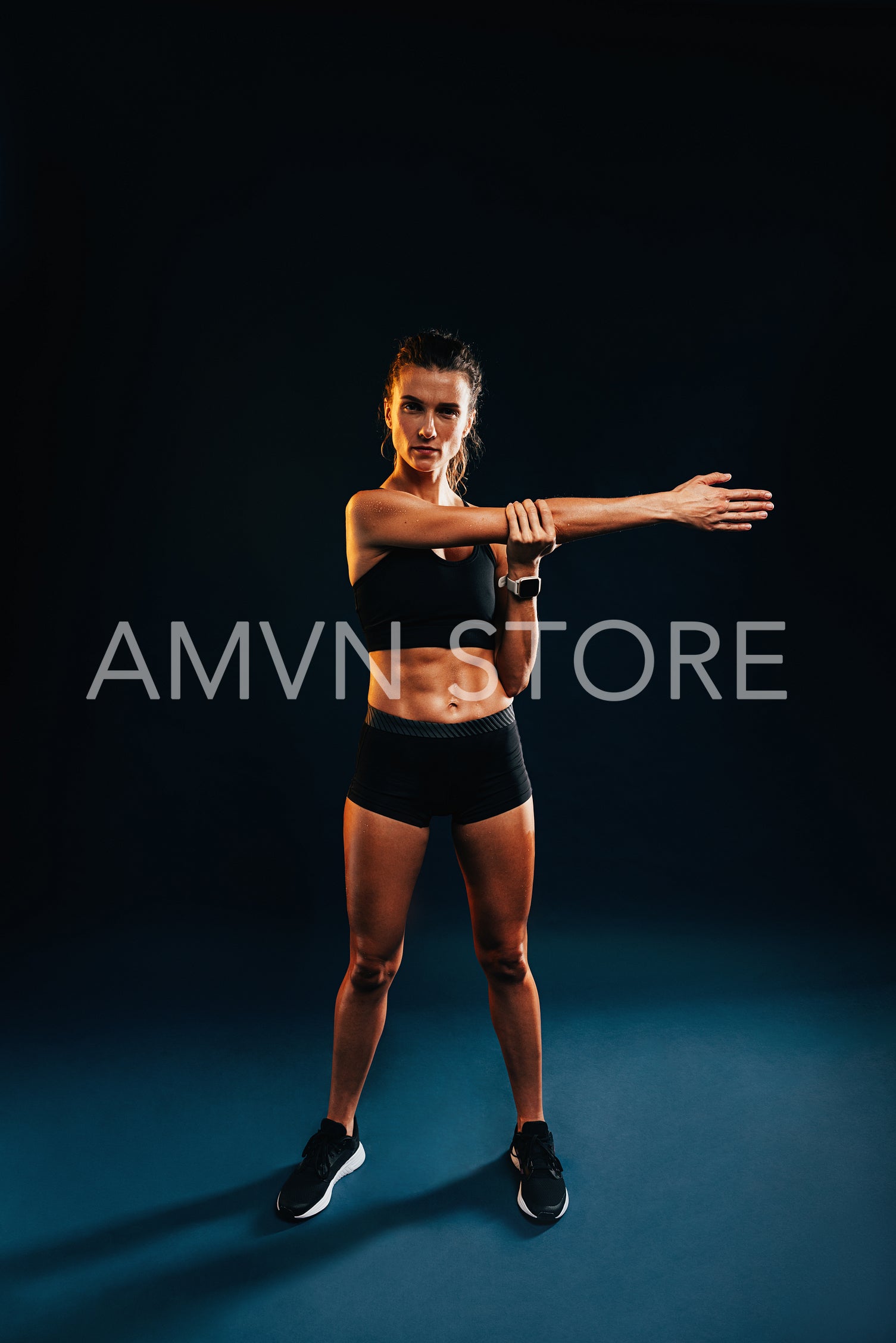 Full length on young woman in fitness wear warming up her hand on black background