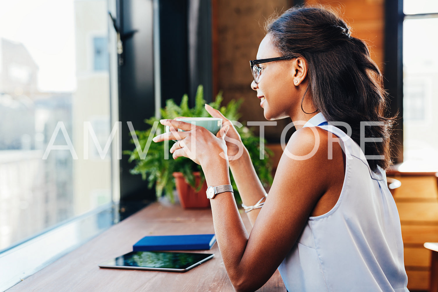 Side view of smiling female having coffee while working in cafe	